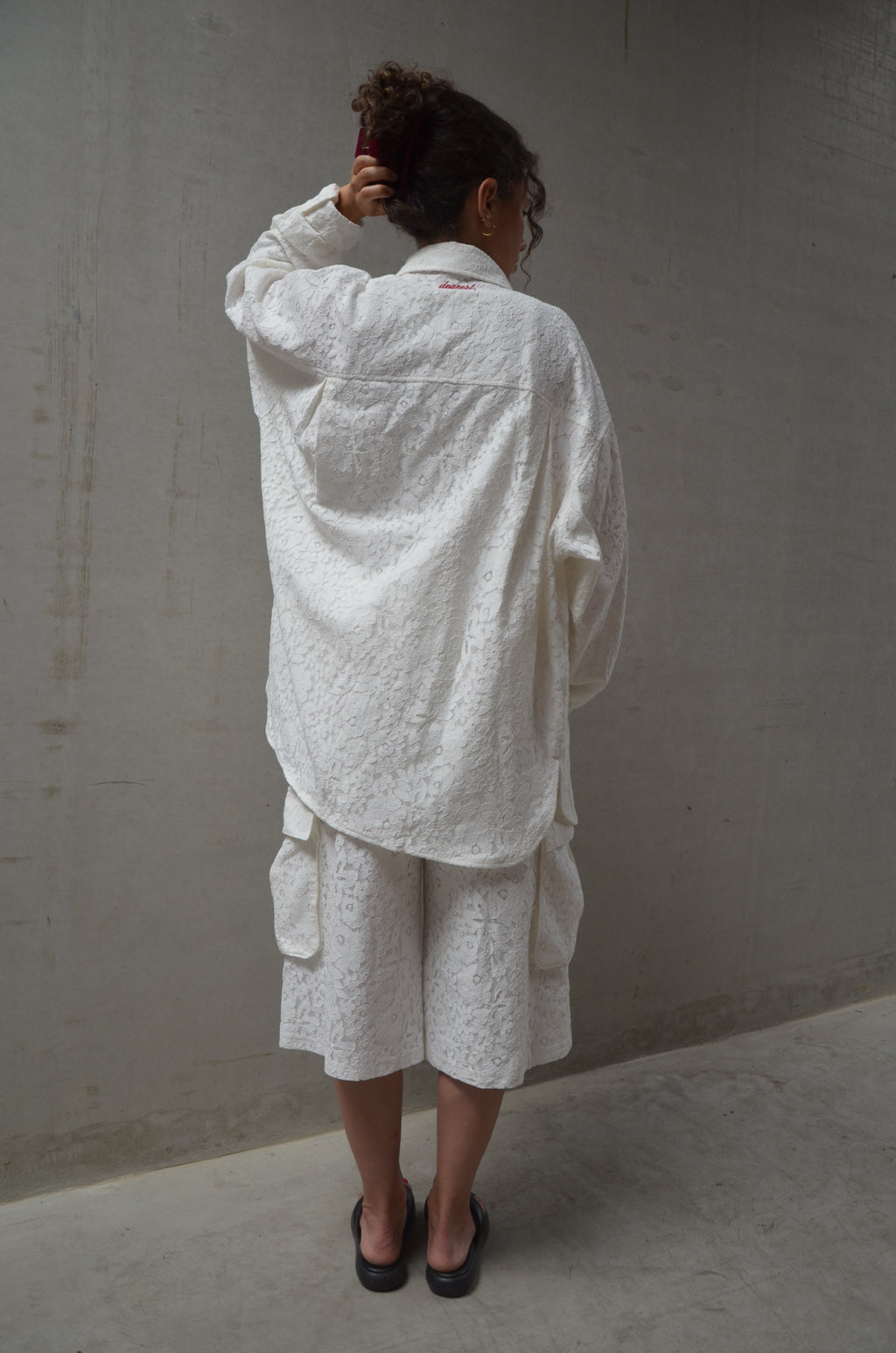 Person wearing a white lace outfit standing on a plain floor.