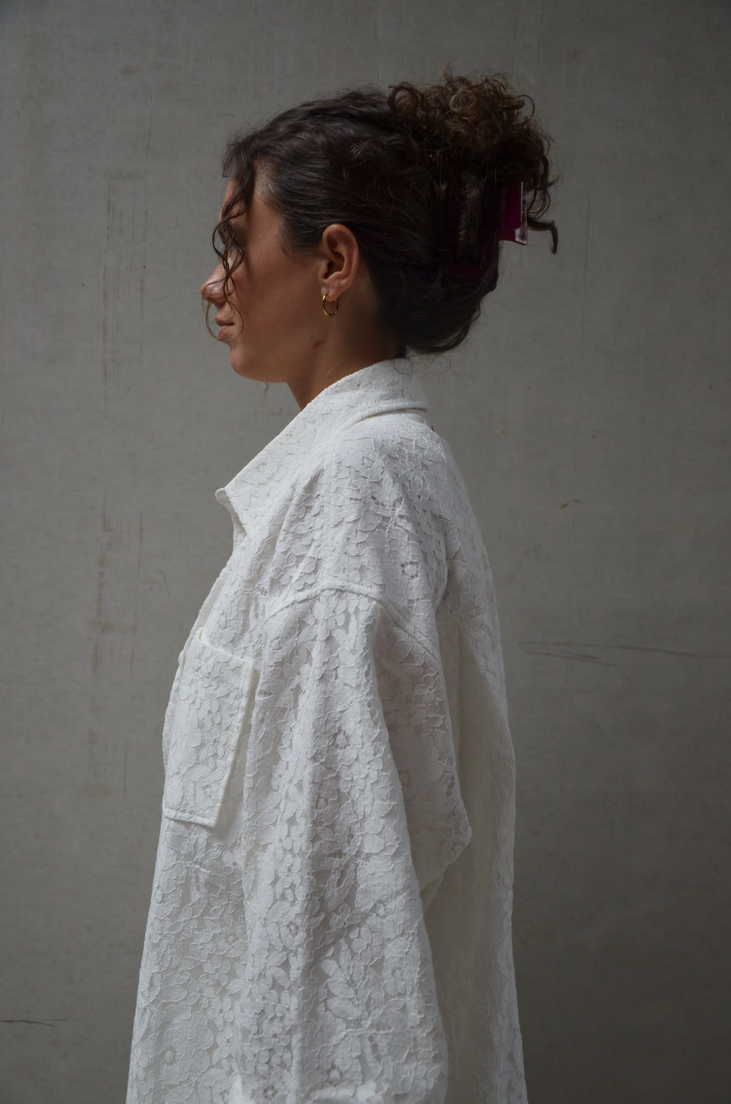 Person wearing a white lace shirt against a plain background
