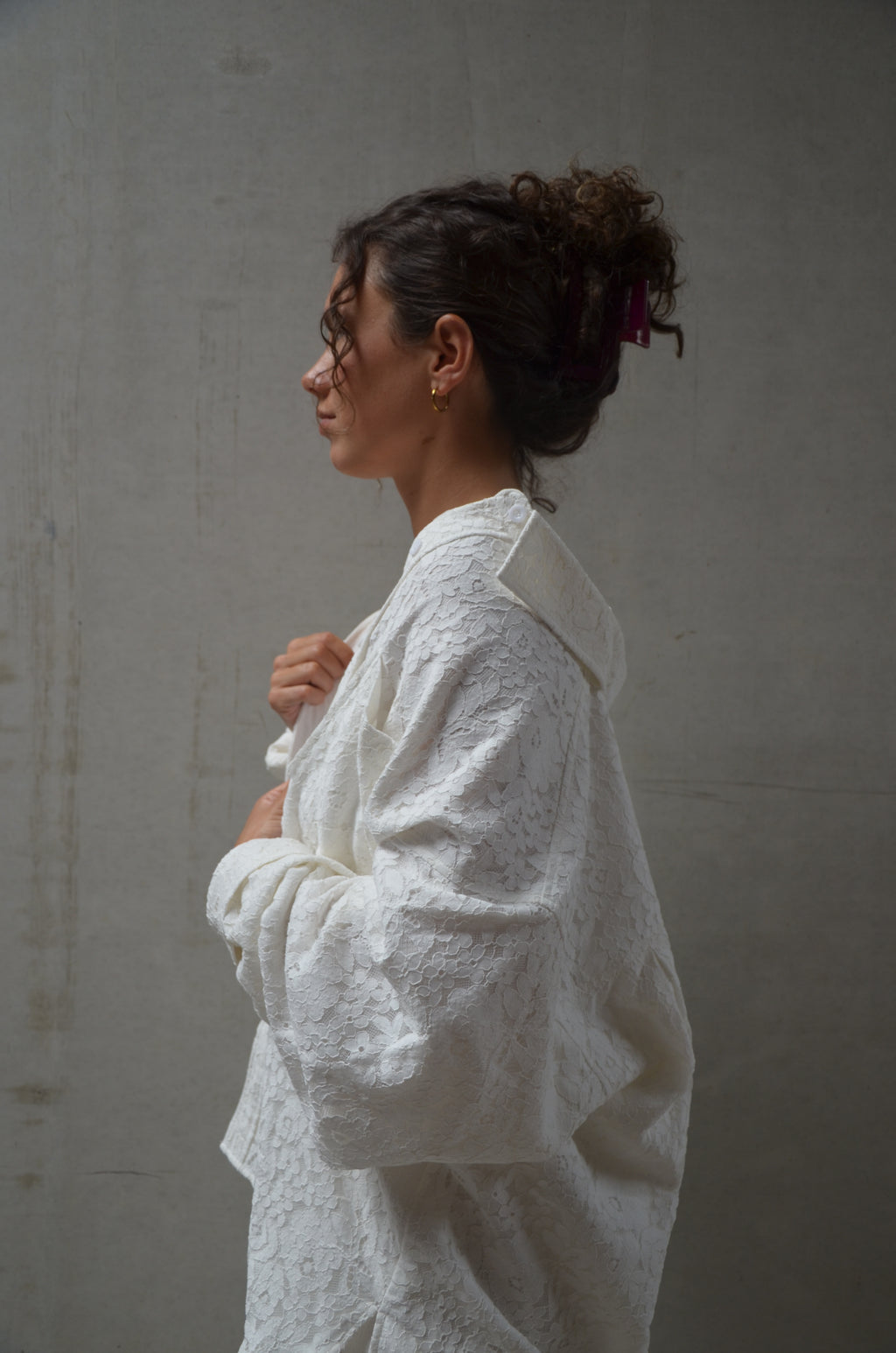 Woman wearing a lace white garment against a plain background