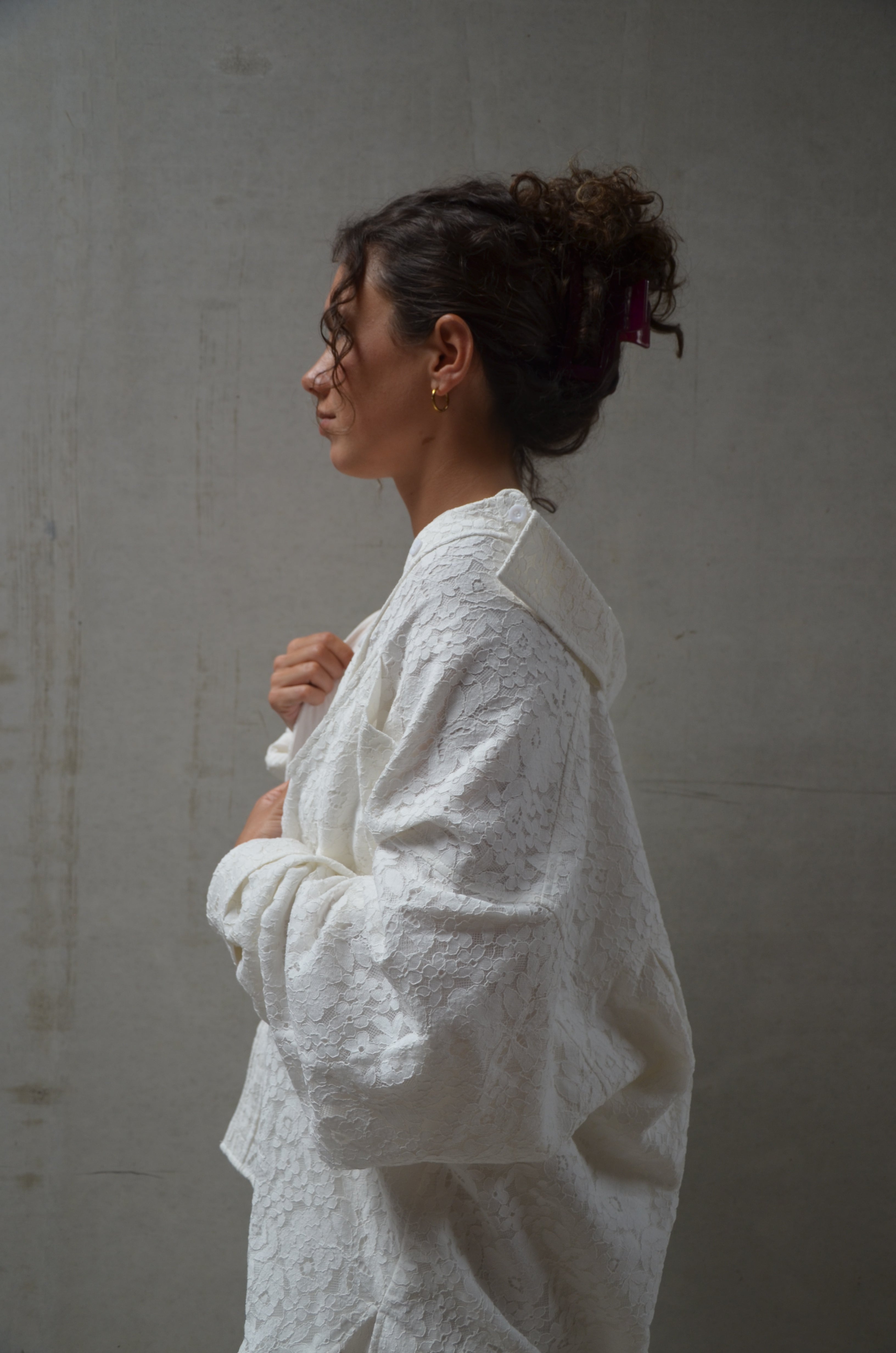 Woman wearing a lace white garment against a plain background