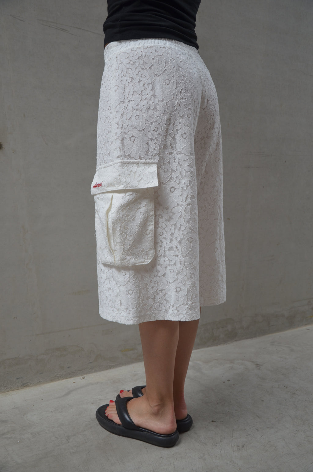 Person wearing white lace shorts with a pattern on a concrete floor