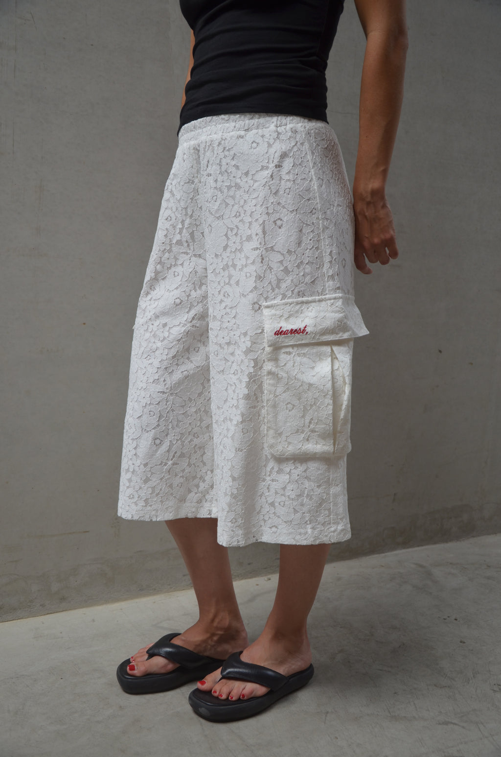 Person wearing a white lace shorts with a black top on a plain background